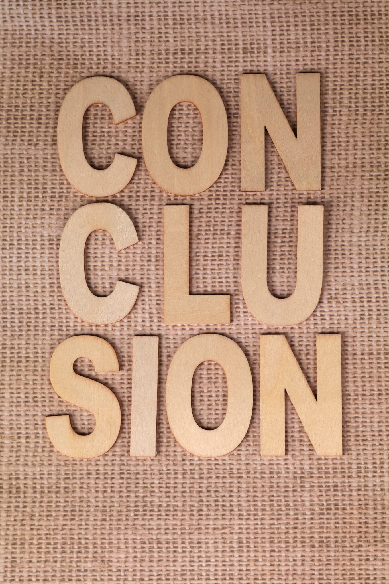 Wooden letters spelling 'CONCLUSION' on textured burlap background.